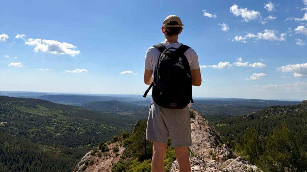 Wanderer mit Rucksack auf einem Felsen über der Landschaft der Provence – Erasmus-Semester in Aix-en-Provence für „studieren weltweit“ des DAAD